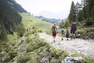 Famile wandert zur Hütte. Die Familie besteht aus Vater, Mutter und zwei Kindern,