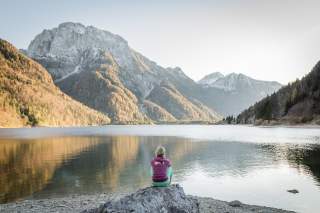 Person sitzt an Bergsee und genießt den Blick