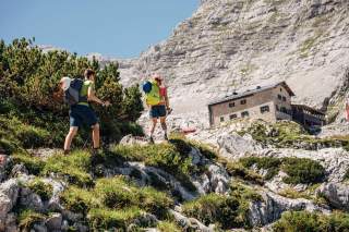 Zwei Bergsteiger kurz vor einer Hütte.