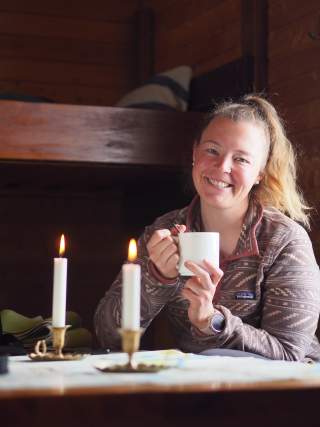 Hüttenwirtin Annika Haak mit einem Tee sitzend in der gemütlichen Hütte.