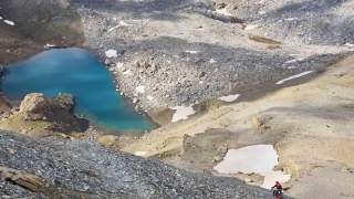 Mountainbiker auf steilem Gerölltrail mit Blick auf blauen Bergsee