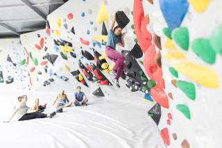 Eine Frau bouldert eine Route in einer Boulderhalle.