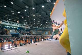 Kletterin hängt an Boulderwand beim Wettkampf