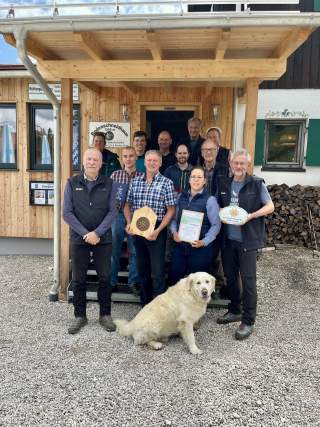 12 Personen und ein Hund stehen für die Verleihung des Umweltgütesiegels vor der Hütte