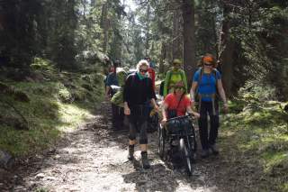 Wandergruppe im Wald mit Rollstuhlfahrerin