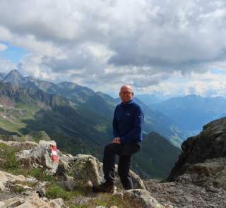 Jens Keen steht auf einem Weg in wunderschöner Alpenlandschaft.