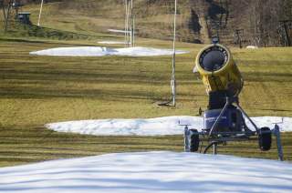 Schneekanone auf grüner Wiese mit wenigen Schneefeldern