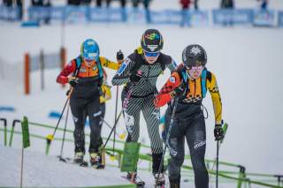 drei Skimo Athletinnen hintereinander im Aufstieg. Man sieht die grün markierten Diamante, die den Kurs vorgeben.