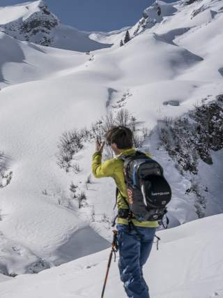 Skitourengeher zeigt auf einen verschneiten Berghang.