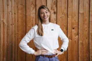 Porträt Annika Seefeld vor Holzwand. Sie trägt ein weißes Langarmshirt.