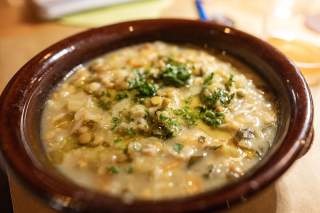 Braune Schale mit warmer Gemüsesuppe, garniert mit gehackter Petersilie.