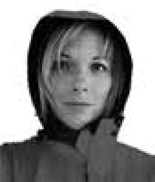 Porträt einer jungen Frau mit kurzem Haar, die eine Kapuzenjacke trägt und direkt in die Kamera schaut.