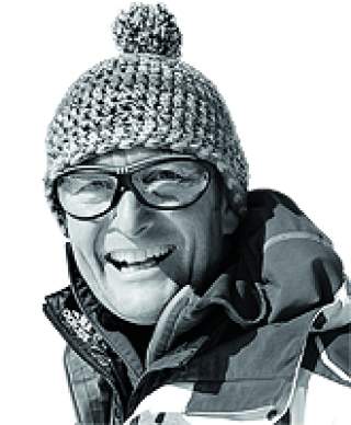 Porträt eines älteren Mannes mit gestrickter Mütze, Brille und Winterjacke, der lächelnd in die Kamera schaut.