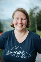 Das Bild zeigt Yvonne Tremmel im blauen T-Shirt mit Werbung für das Brünnsteinhaus. Sie blickt lächelnd in die Kamera.