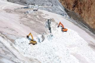Große Bagger stehen auf Gletscherfläche und graben Gletscher um